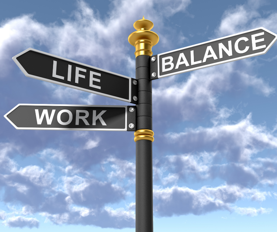 Znak drogowy z trzema czarnymi tabliczkami z napisami „LIFE”, „WORK” i „BALANCE” na tle nieba z chmurami, symbolizujący poszukiwanie równowagi między życiem zawodowym a prywatnym u menedżerów.